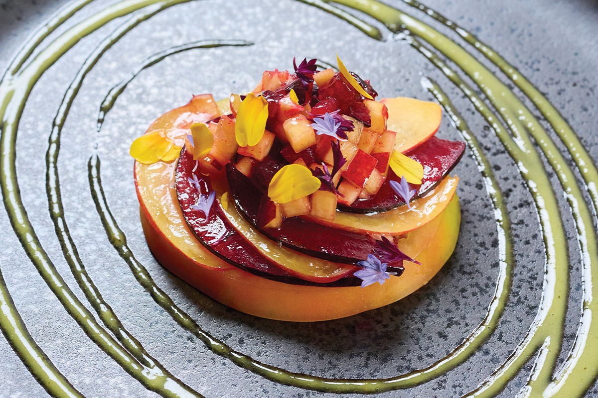 Close-up shot of a wheel of smoked Manchego cheese drizzled with saffron-infused honey, garnished with fresh herbs