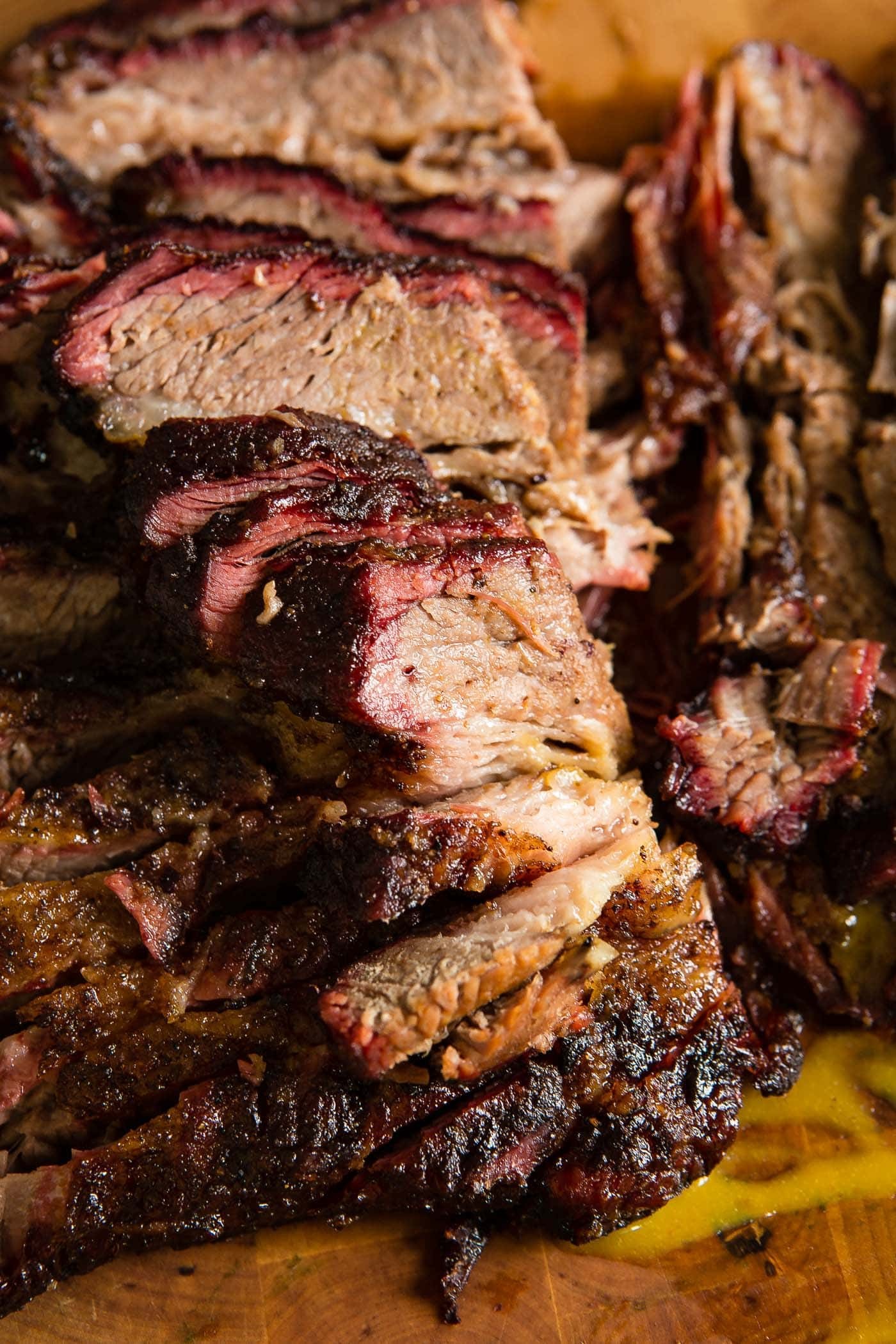 Close-up shot of a perfectly smoked brisket, glistening and tender, with visible garlic and herbs