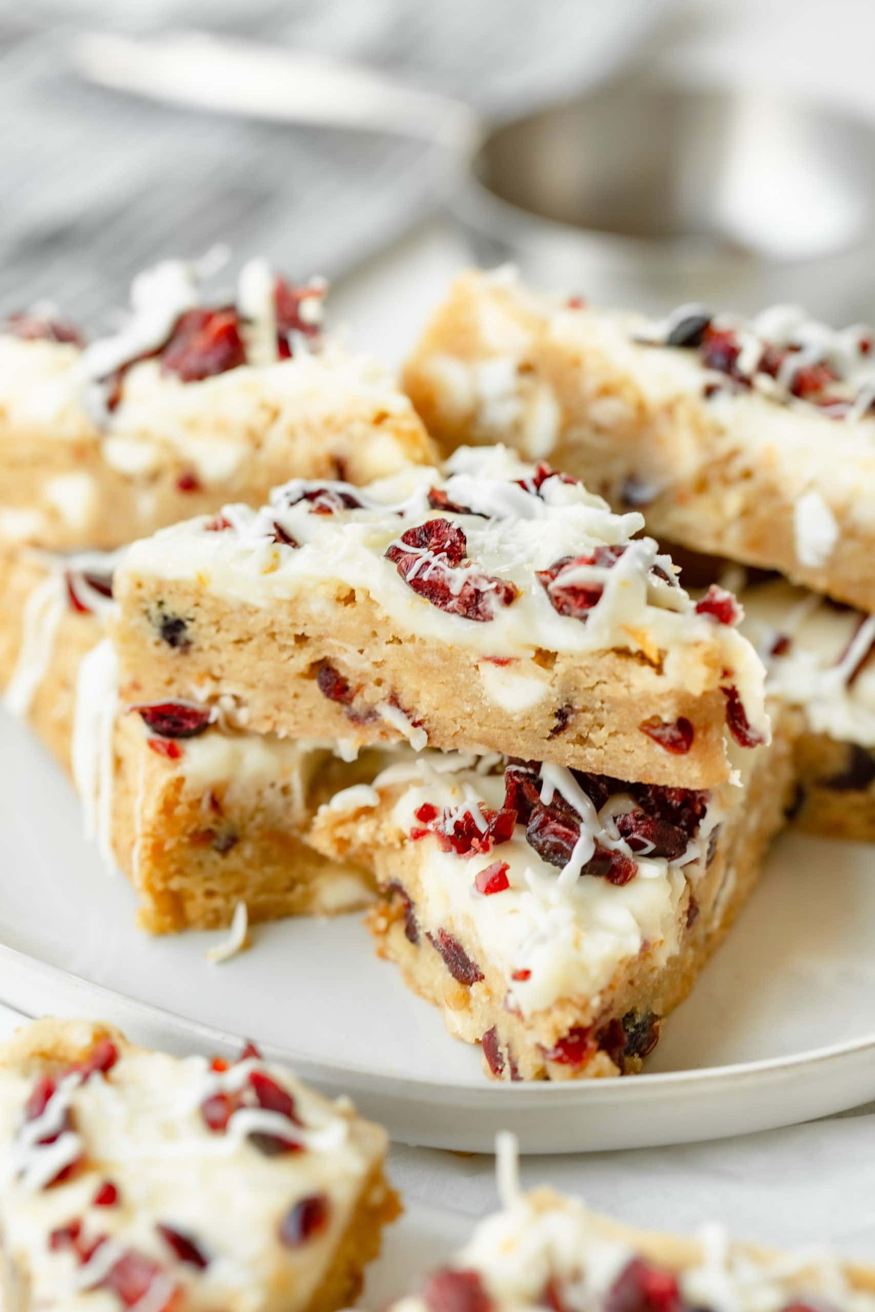 vibrant cranberry bliss bars on a rustic wooden board, garnished with white chocolate drizzle and orange zest, cozy kitchen background