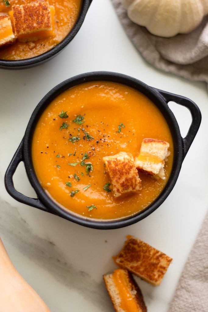 hearty Thanksgiving harvest vegetable soup with croutons and herbs, cozy autumn setting, warm lighting