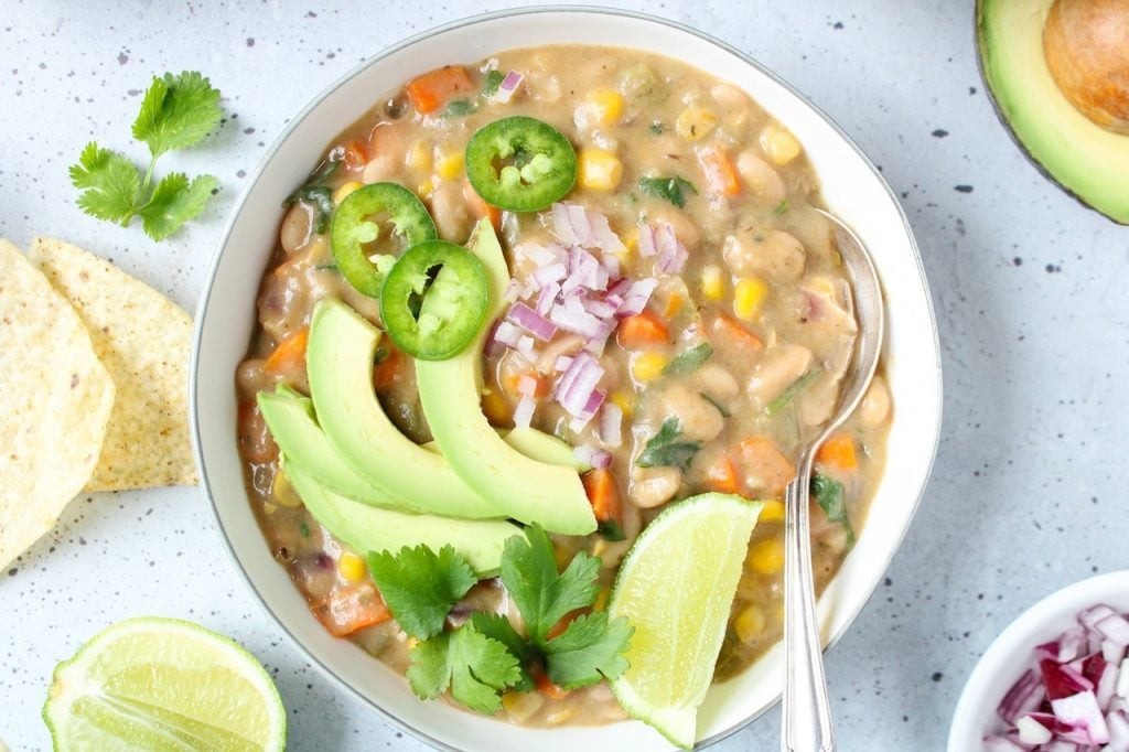 a bowl of barley and white bean chili garnished with lime and cilantro