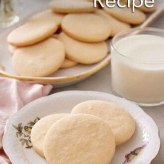 beautifully decorated classic sugar cookies stacked on a plate, with a glass of milk in the background, warm kitchen lighting