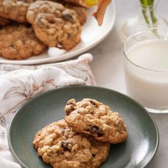 plate of soft chewy oatmeal raisin cookies, warm kitchen background, glass of milk