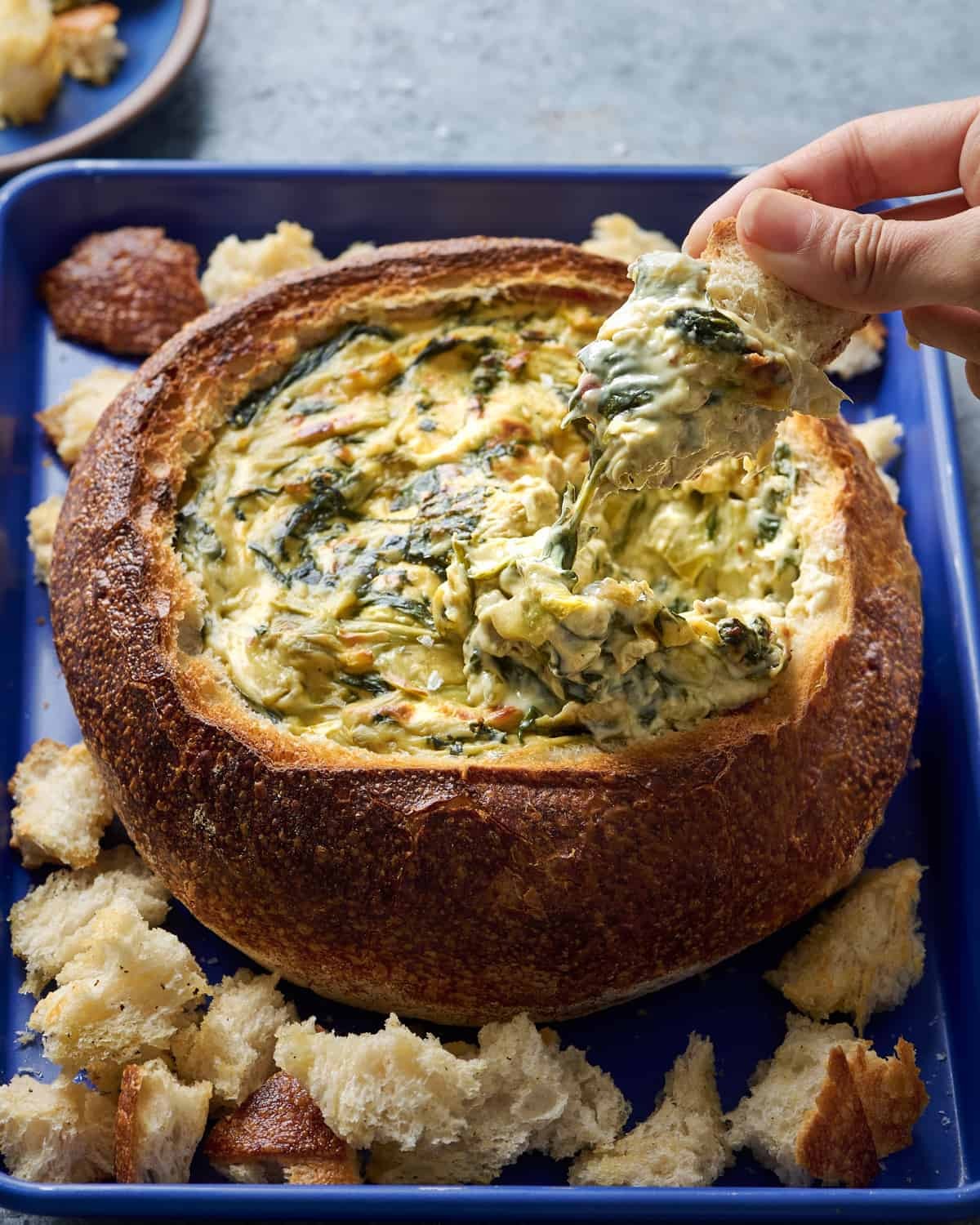 Warm, bubbly spinach artichoke dip with melted golden-brown cheese topping, served with crusty bread and tortilla chips