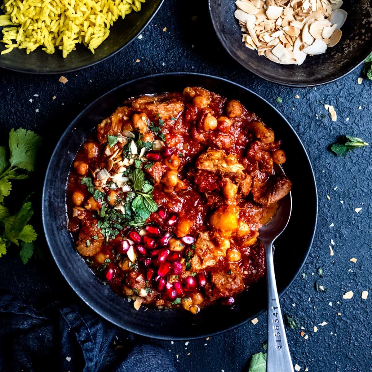 Close-up shot of a vibrant, steaming Spicy Lamb Tagine with Chickpeas and Spinach in a rustic pot, garnished with fresh cilantro