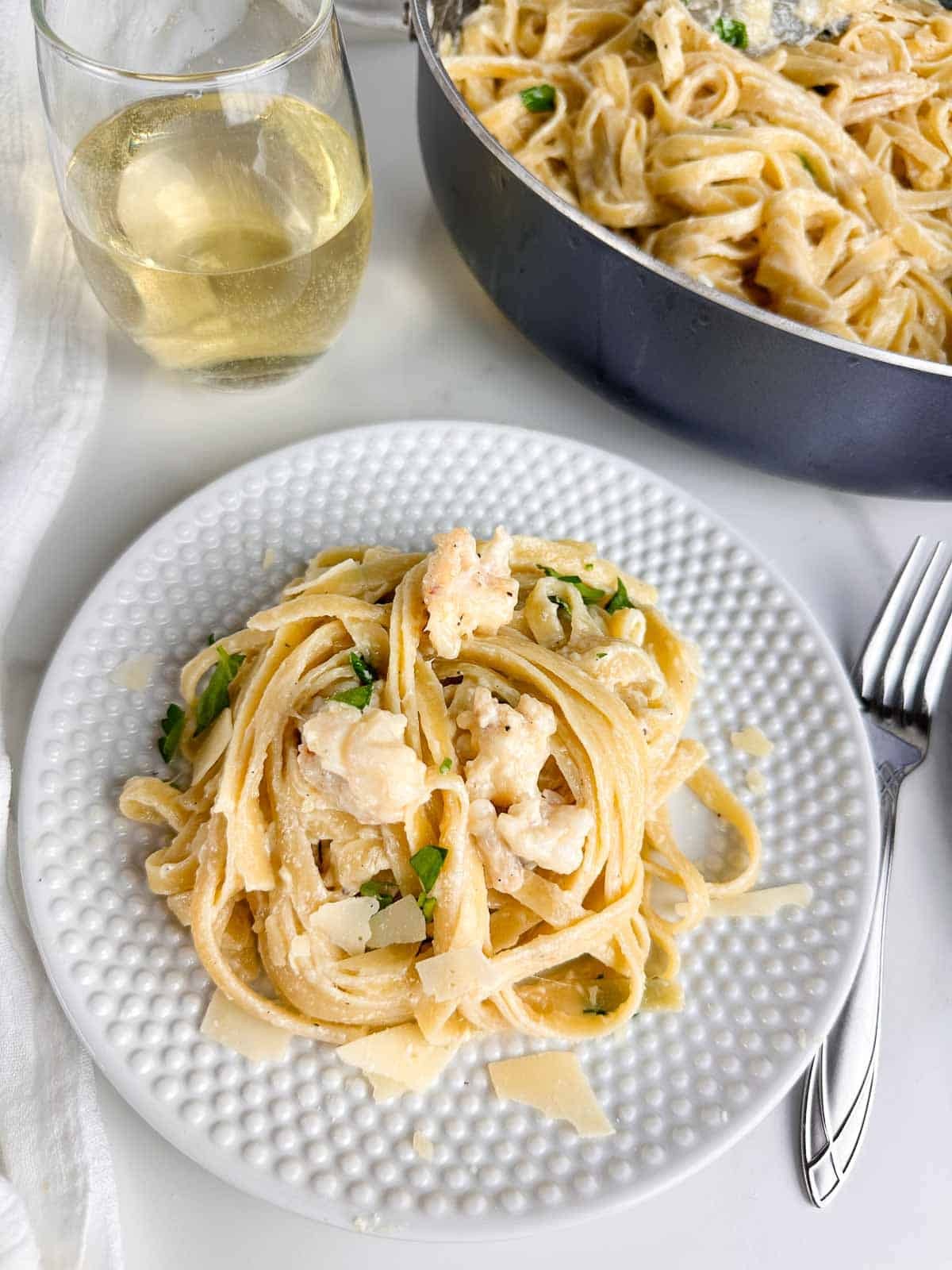 A plate of anniversary lobster fettuccine alfredo, garnished with fresh parsley