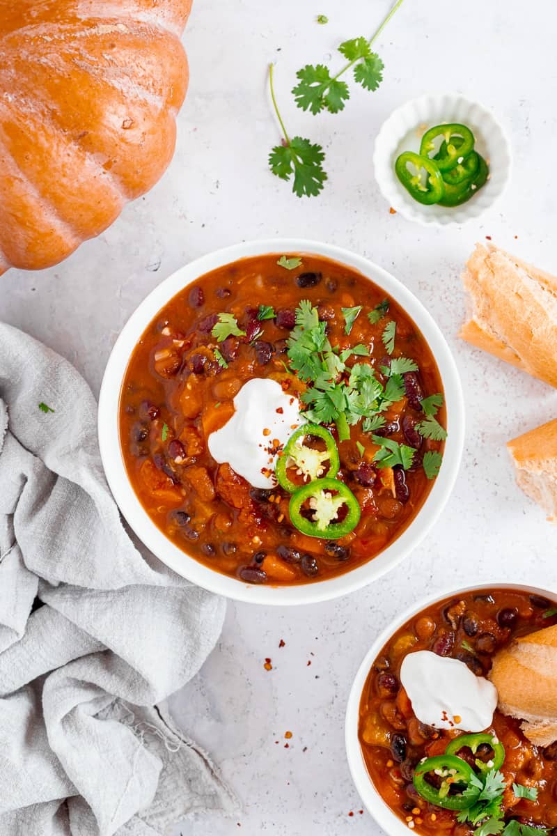 A hearty bowl of pumpkin chili garnished with cilantro and a dollop of sour cream