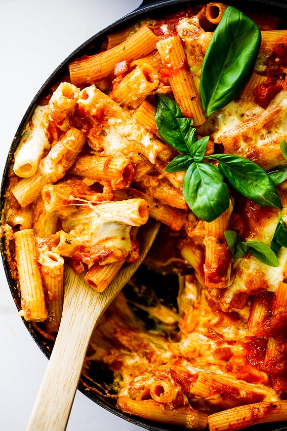 Warm cheesy baked ziti casserole, garnished with fresh basil