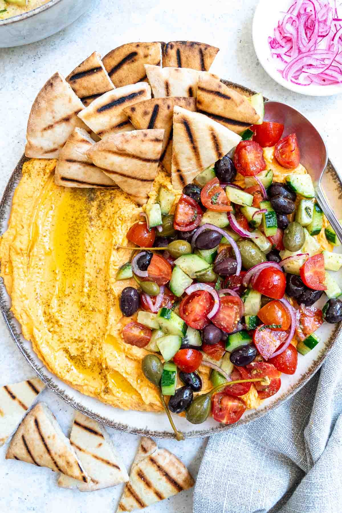 Vibrant loaded Mediterranean hummus dip with pita bread and vegetables on a rustic wooden table