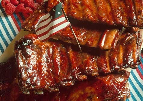 Close-up shot of delicious, glazed maple-mustard smoked ribs, glistening with sauce, on a wooden board.