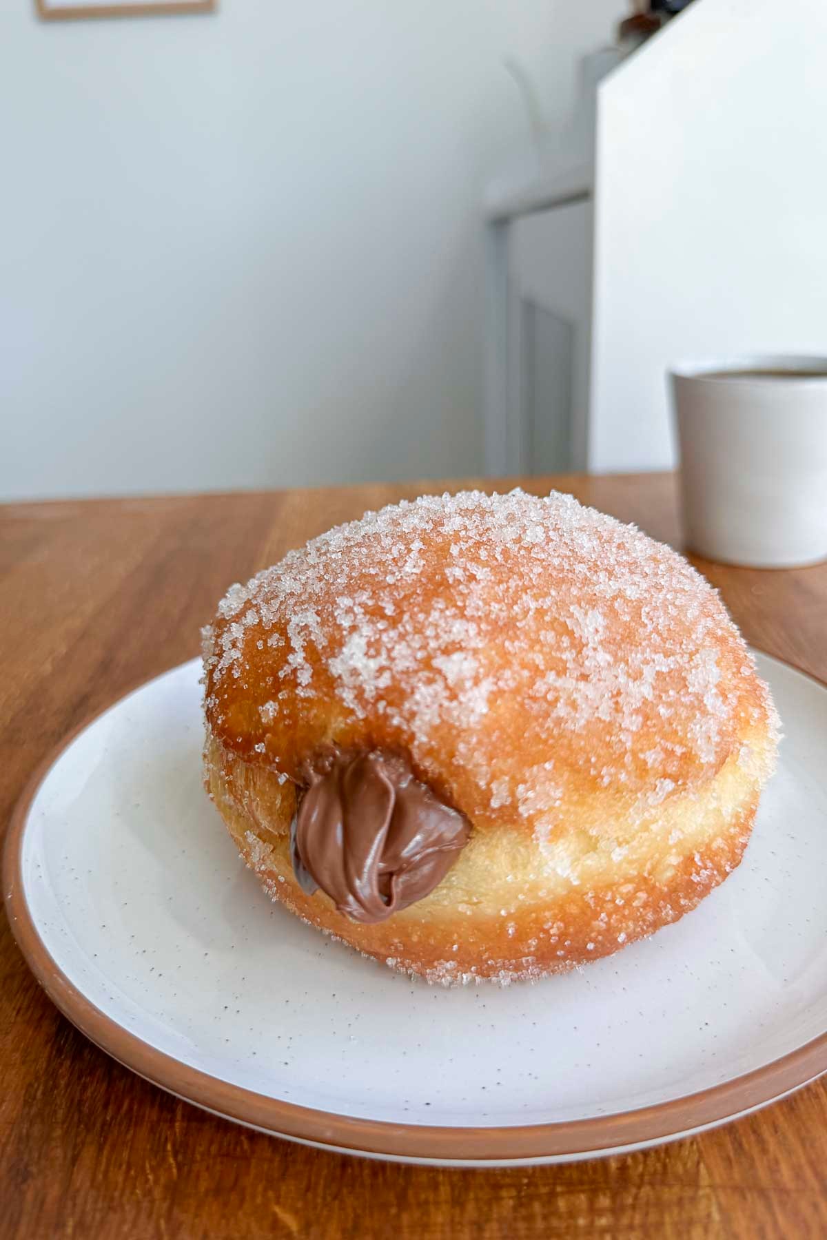 Close-up shot of golden-brown Nutella-stuffed churros donuts dusted with powdered sugar, arranged on a parchment-lined baking sheet.