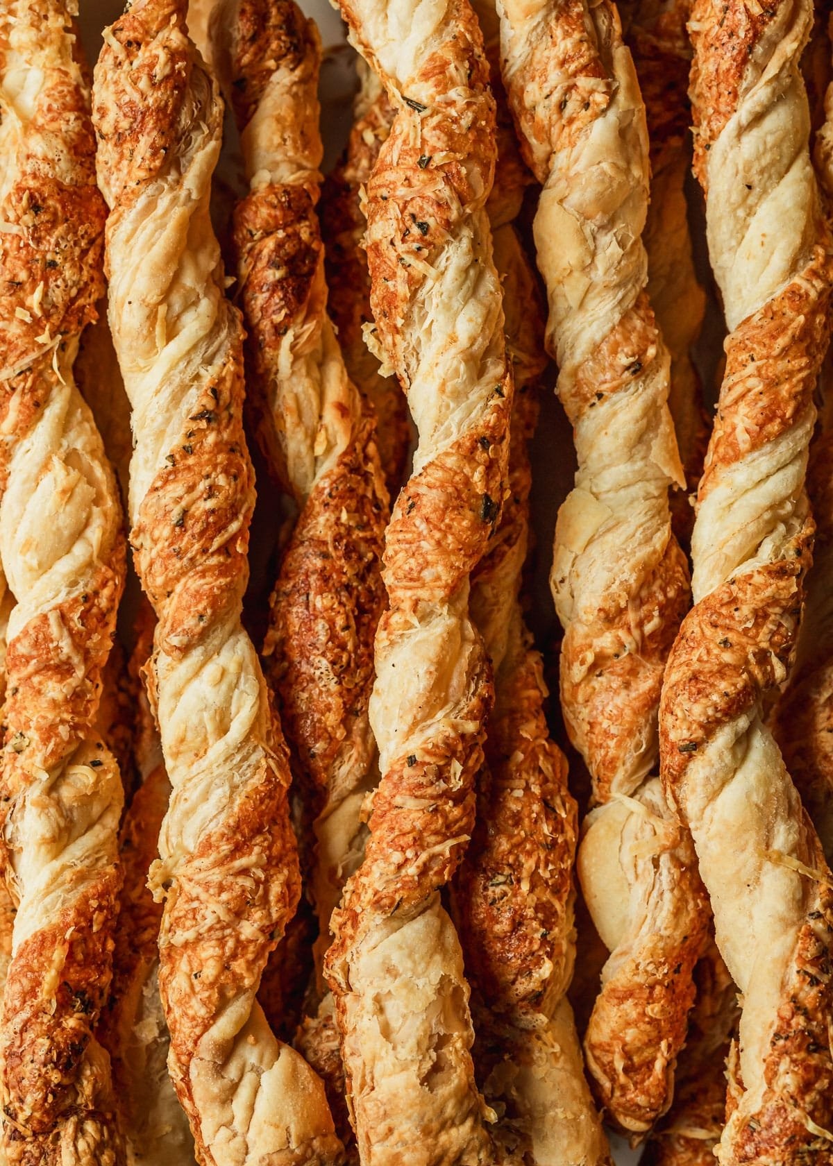 Golden brown parmesan puff pastry twists on a cooling rack, close-up, appetizing