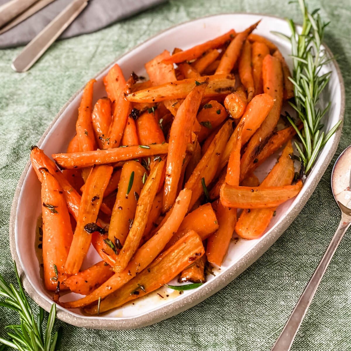 Close-up shot of glistening honey-glazed rosemary carrots on a baking sheet