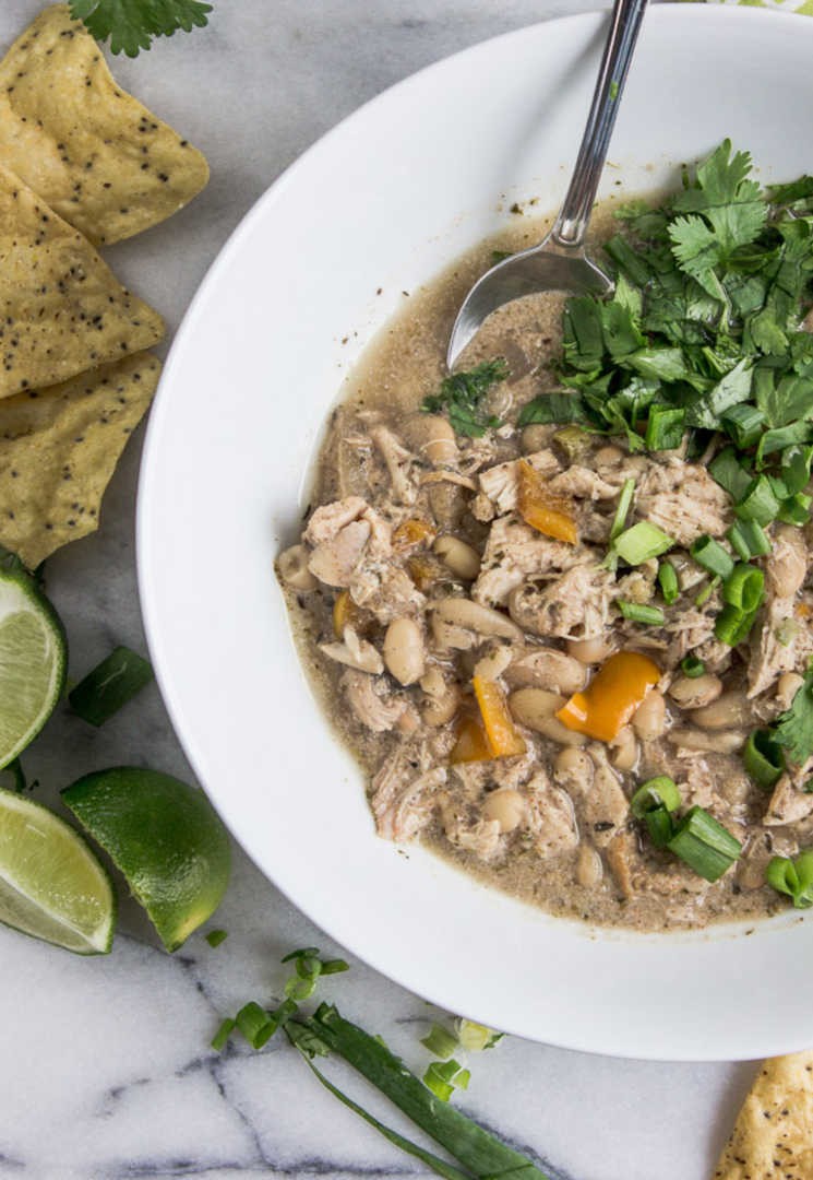A rustic bowl of jerk chicken chili with toasted pepitas on top, garnished with cilantro