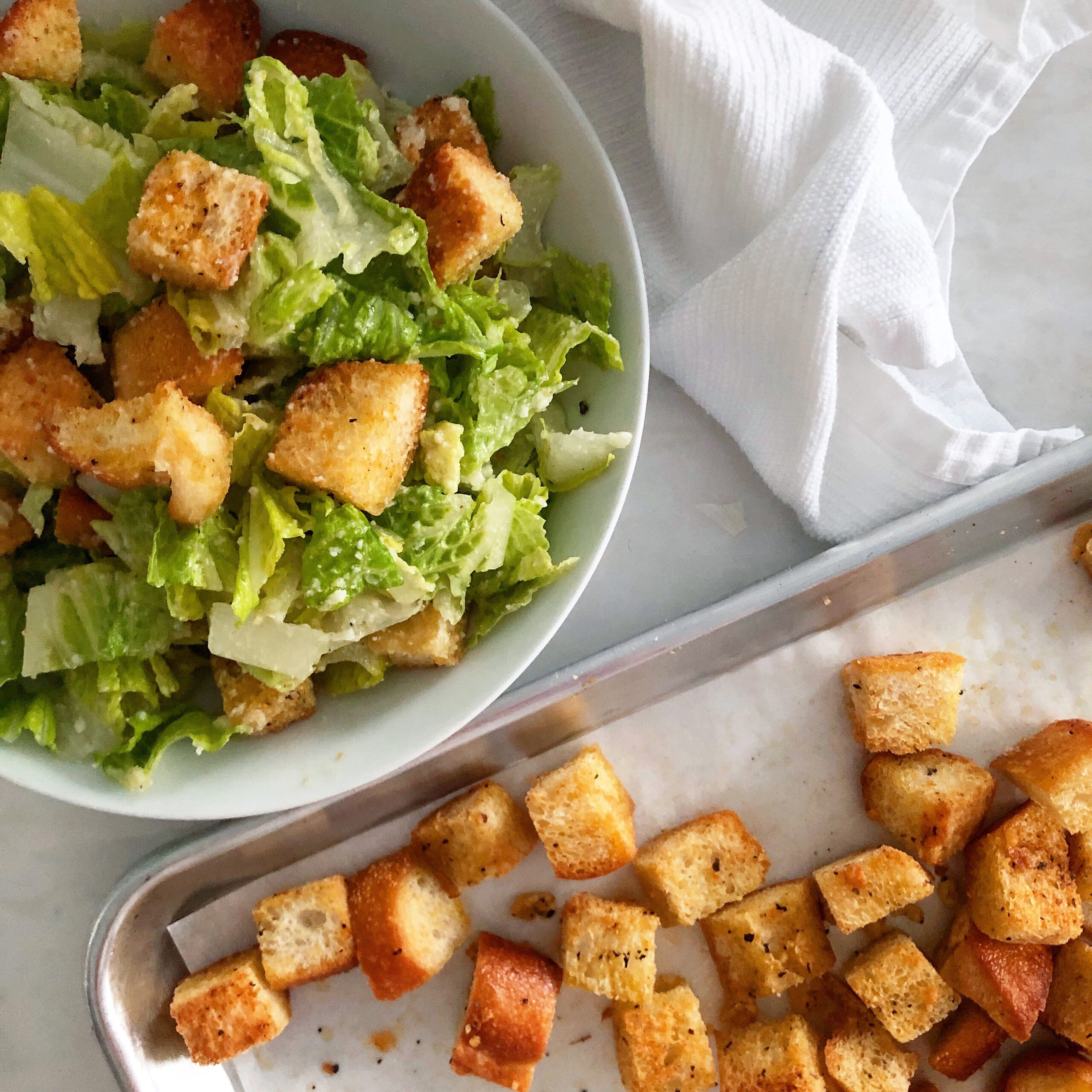 A vibrant Caesar salad with homemade croutons in a large bowl, garnished with parmesan cheese and herbs.