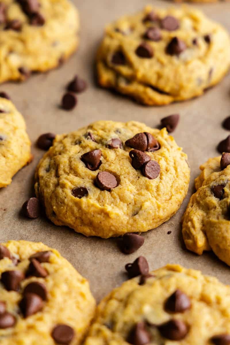 close-up of pumpkin chocolate chip cookies on a baking sheet with a fall-themed background