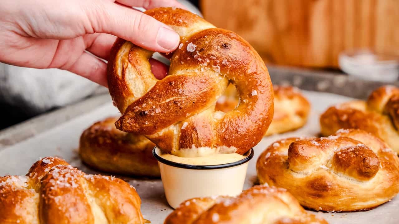 freshly baked soft pretzel twists with melted butter and coarse salt on a wooden board