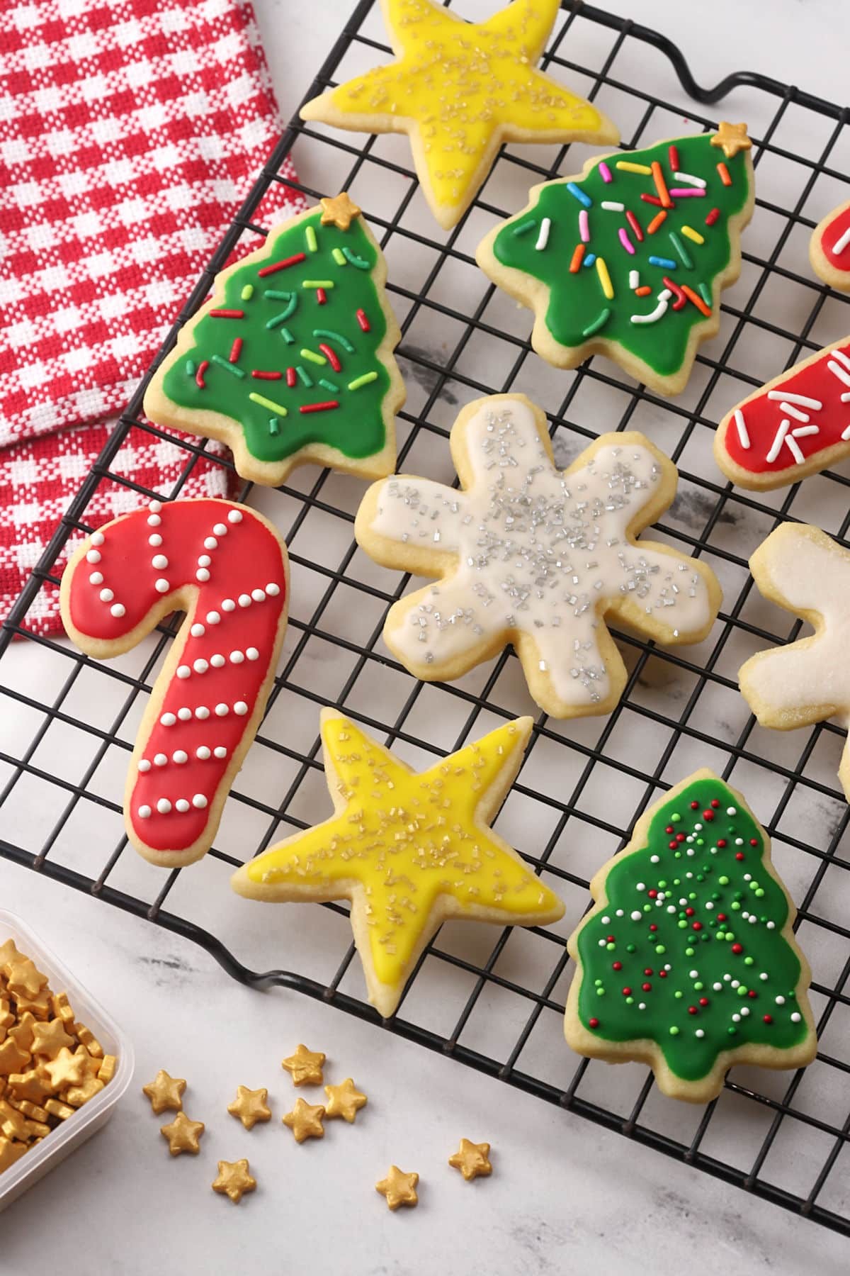Festive star-shaped sugar cookies with vibrant, colorful glaze and sprinkles on a cooling rack