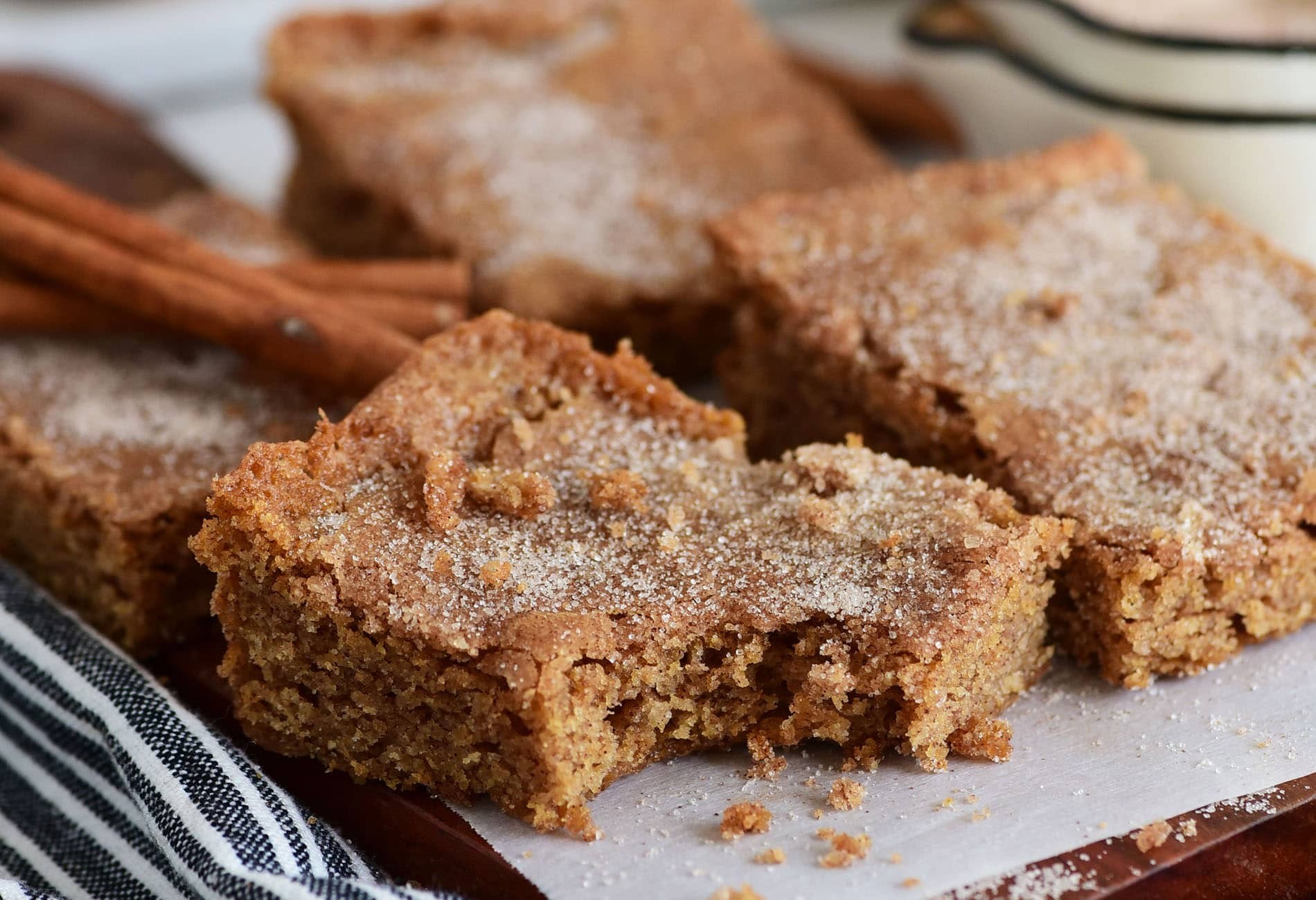 plate of gooey cinnamon cookie squares with frosting, warm cozy kitchen background