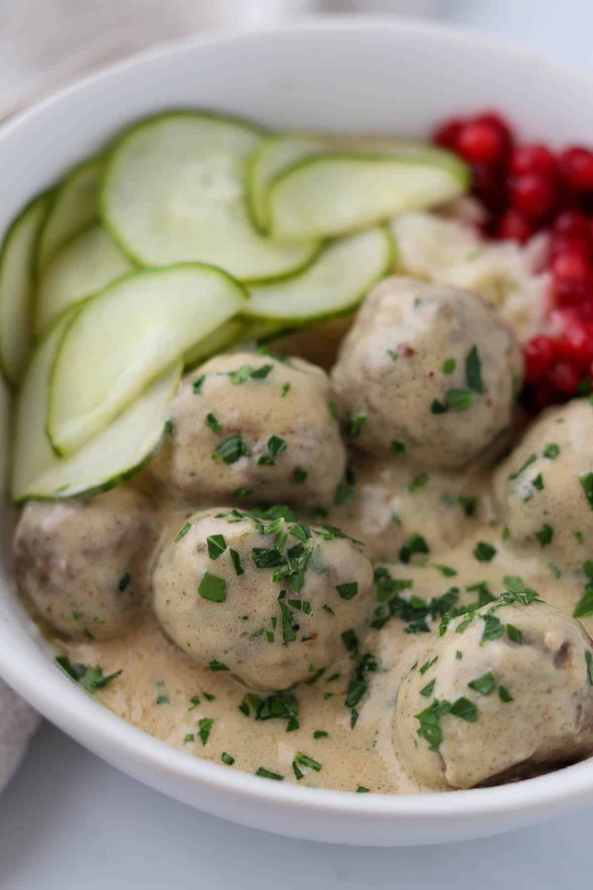 Close-up shot of delicious coconut kötbullar served with creamy sauce and lingonberry jam