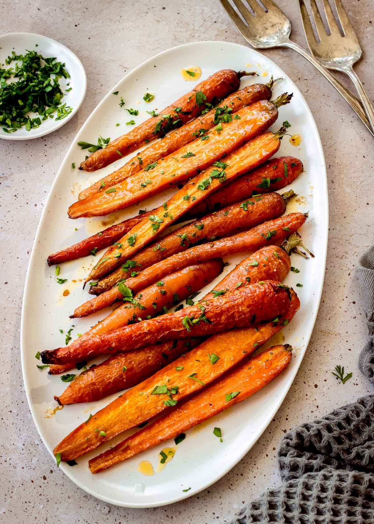 Roasted maple glazed carrots with fresh herbs in a festive ceramic dish on a rustic wooden table, Thanksgiving setting, warm lighting