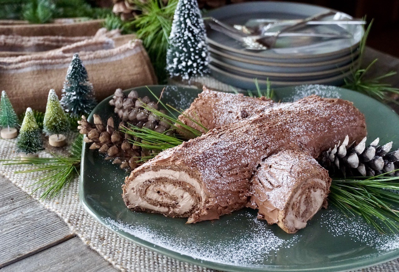 Festive holiday chocolate loaf, dusted with powdered sugar, on a wooden cutting board with pinecones and fairy lights