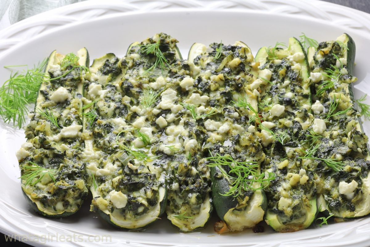 Spanakopita stuffed zucchini boats on a rustic wooden table