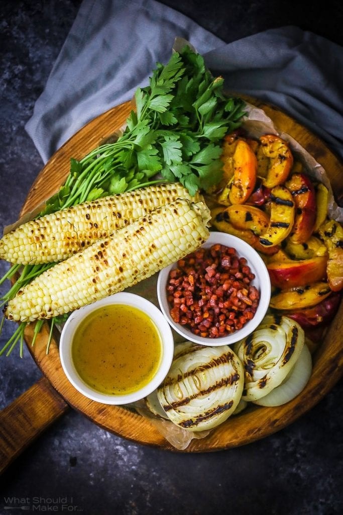 Grilled corn and peach salad with honey mustard dressing on a rustic wooden table