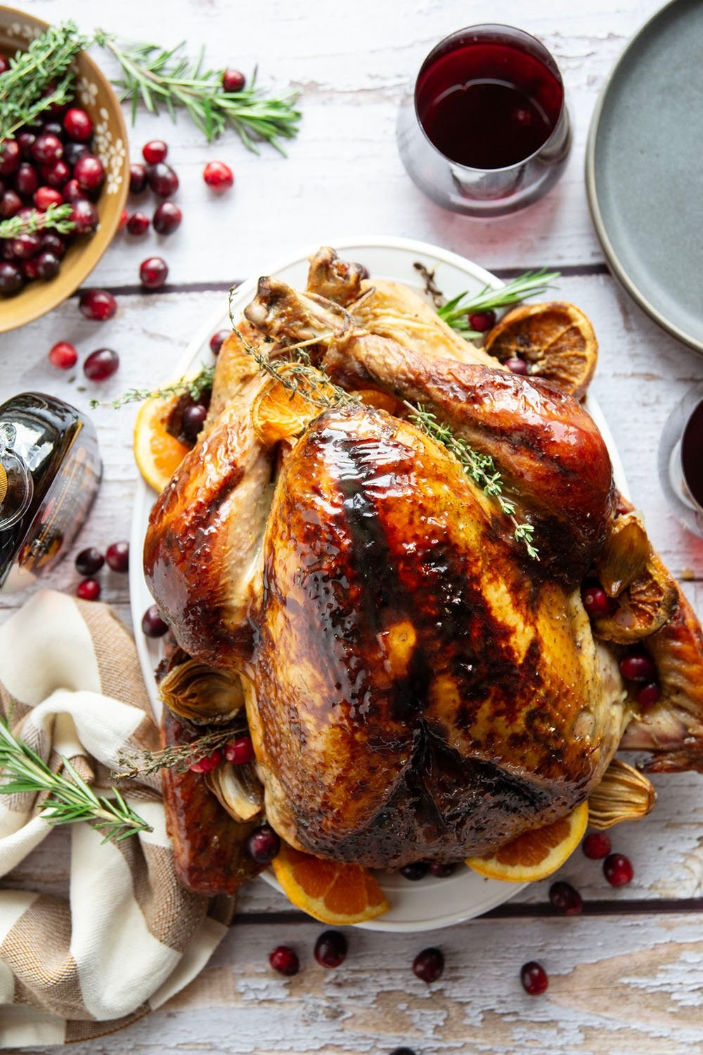 Whole roasted turkey with golden maple glaze, vibrant citrus slices, and fresh herbs, presented on a festive table setting.