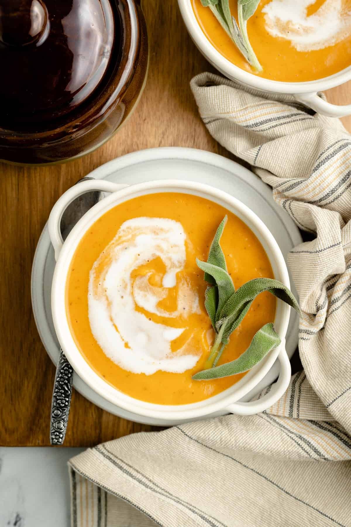 bowl of creamy pumpkin soup with roasted garlic cloves and thyme sprigs