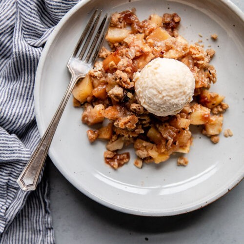 A golden-brown apple crisp with a hazelnut filling bubbling in a baking dish