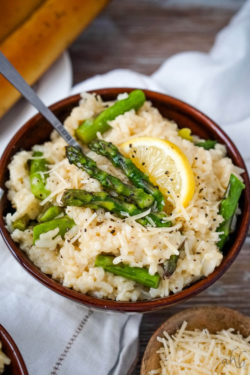 A vibrant and delicious bowl of Asparagus Risotto with Wild Rice, garnished with fresh herbs and parmesan cheese, shot with a shallow depth of field.