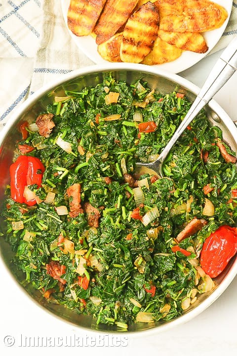 A vibrant, steaming pot of Callaloo and Ground Provision, garnished with fresh herbs.