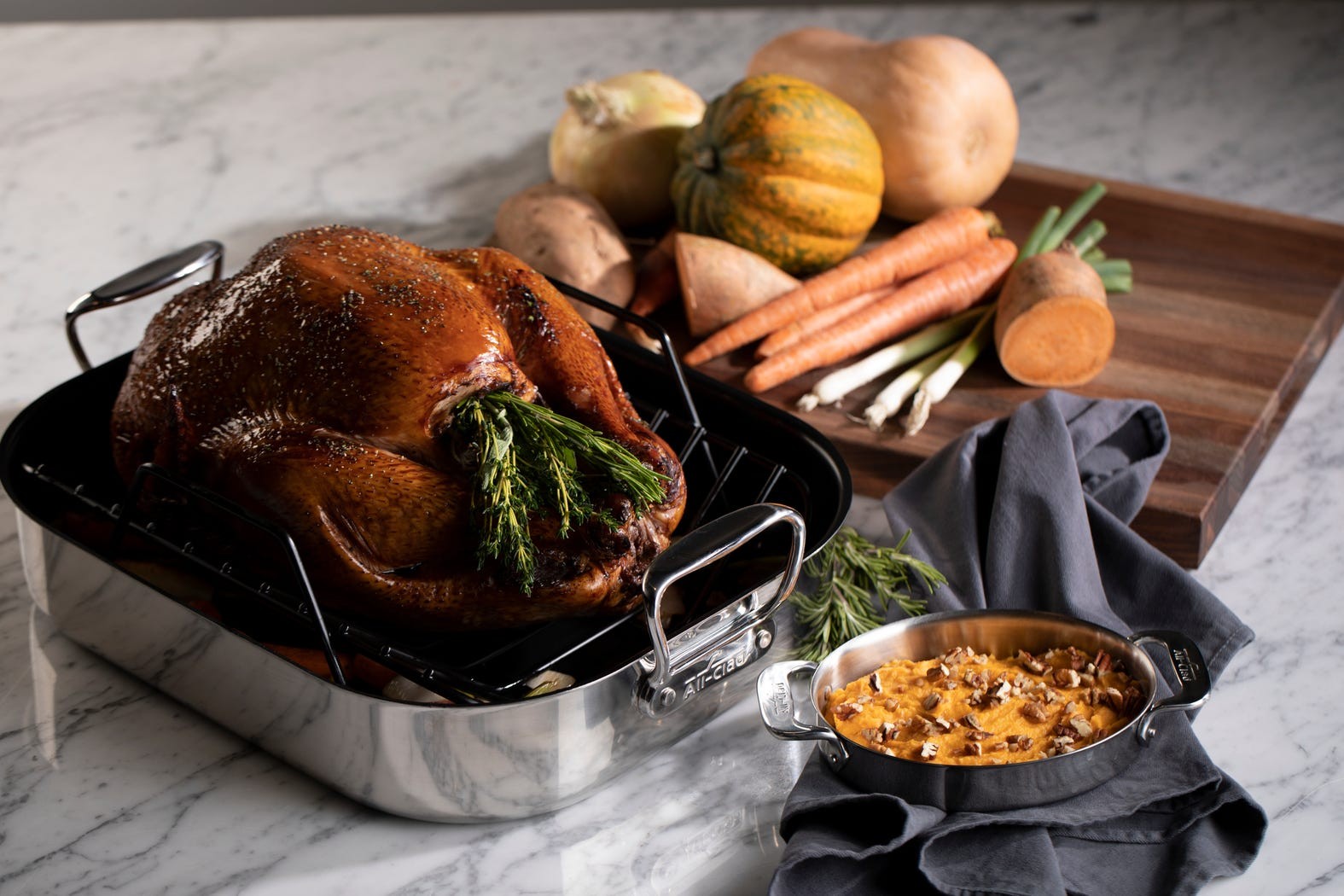Whole roasted turkey with crispy skin in a cast iron pan, surrounded by herbs, rustic setting