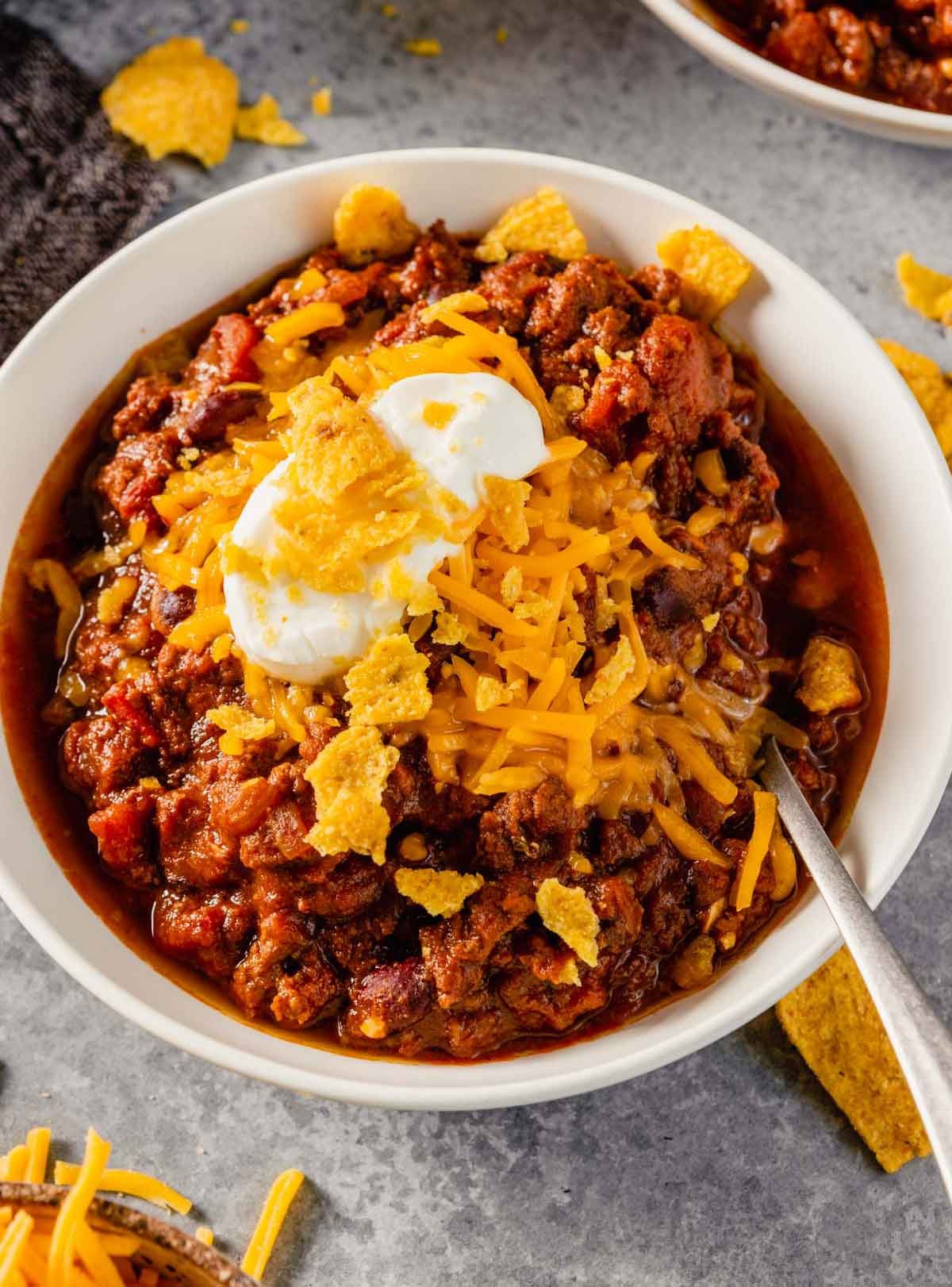 close up shot of a bowl of beef and bean chili with toppings