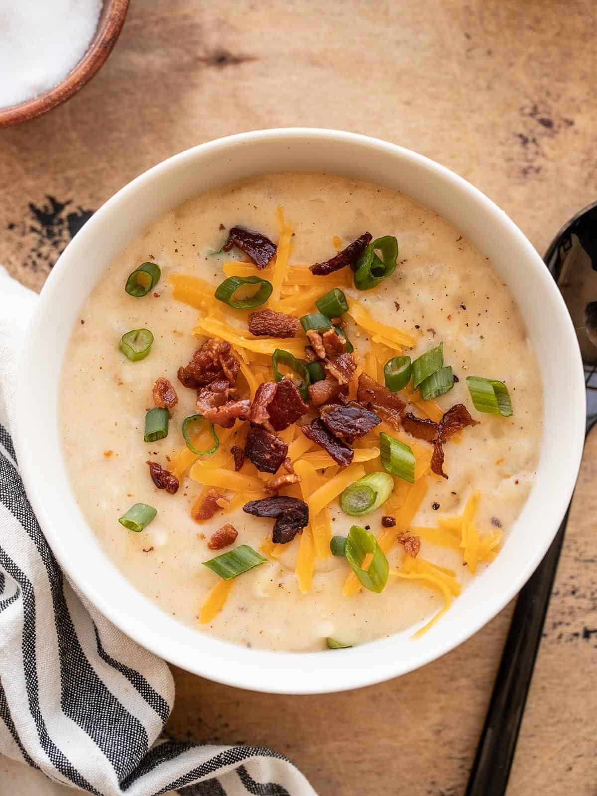 bowl of creamy loaded potato soup with bacon, cheese, and green onions