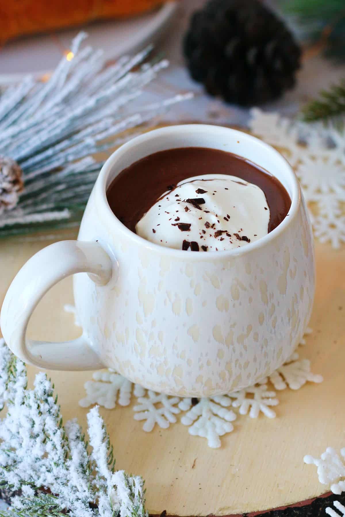 steaming mug of white chocolate cocoa with whipped cream and chocolate shavings on a cozy table