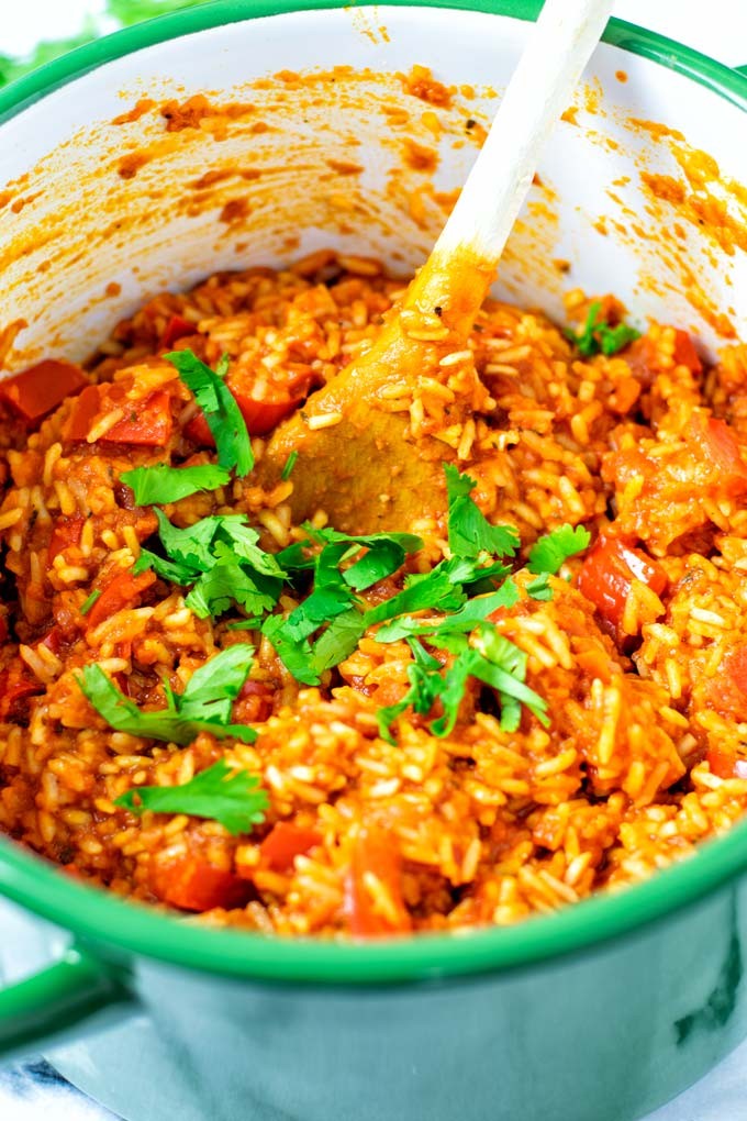 A vibrant pot of Jollof rice with oats, garnished with fresh parsley