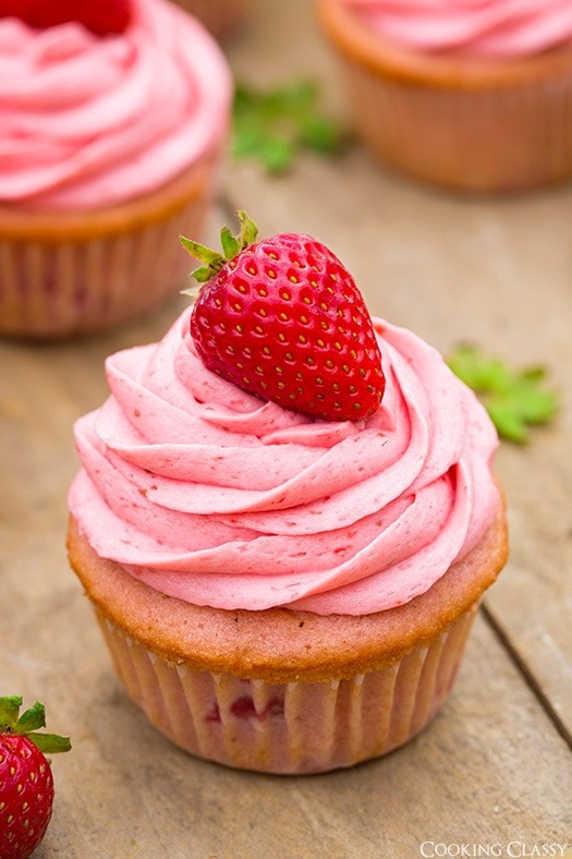 Close-up shot of strawberry cupcakes with strawberry buttercream frosting, decorated with fresh strawberries