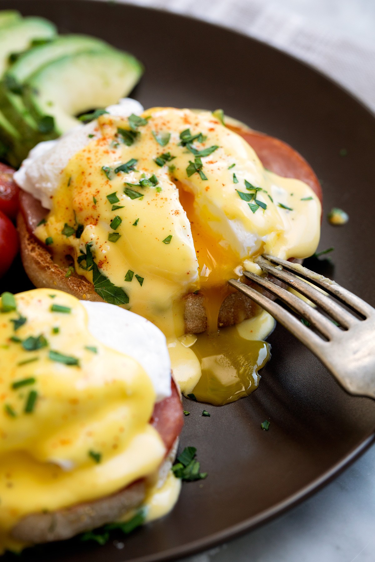 Close-up shot of Eggs Benedict with a vibrant green parsley hollandaise sauce, showing the runny yolk