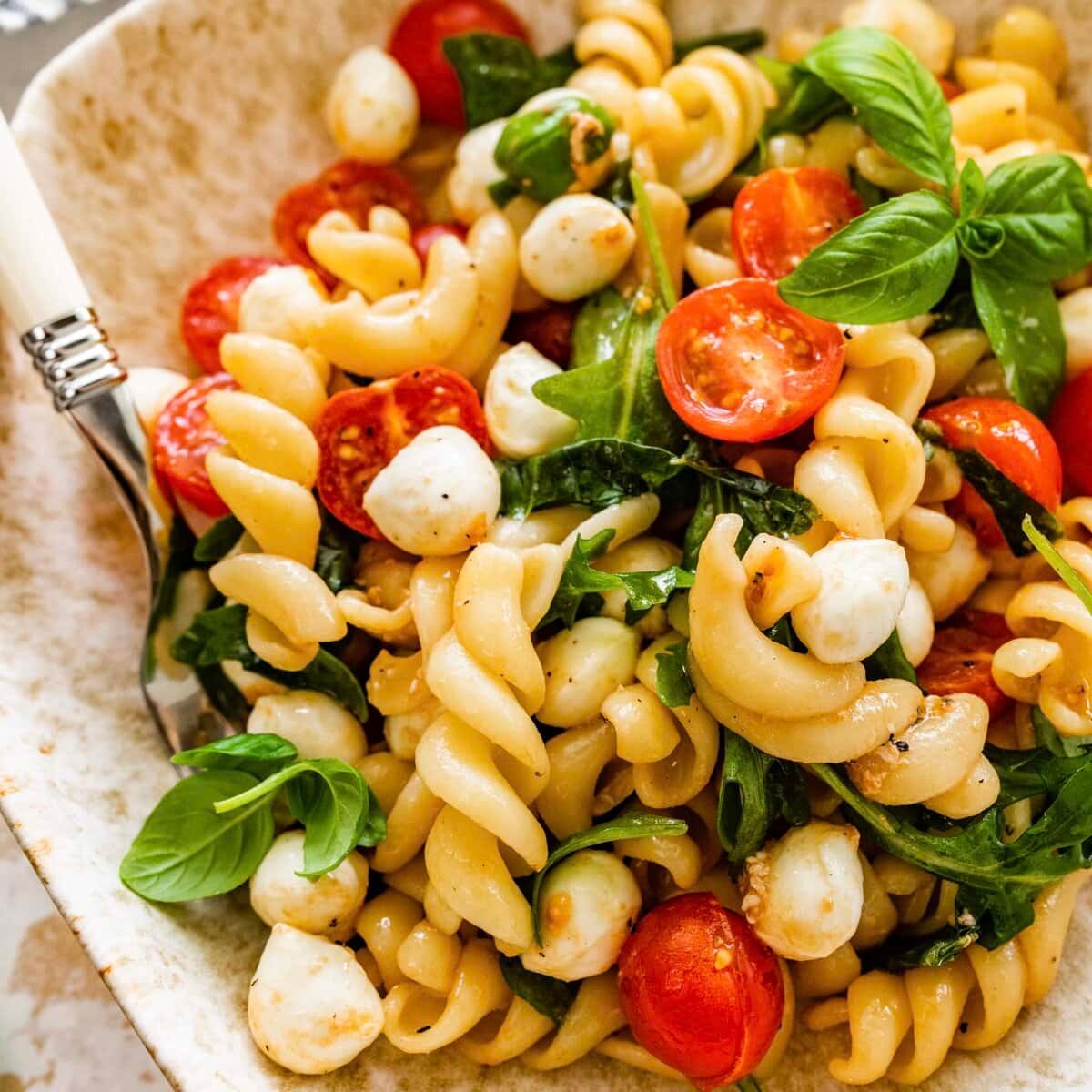 buffalo mozzarella and tomato pasta salad on a rustic table
