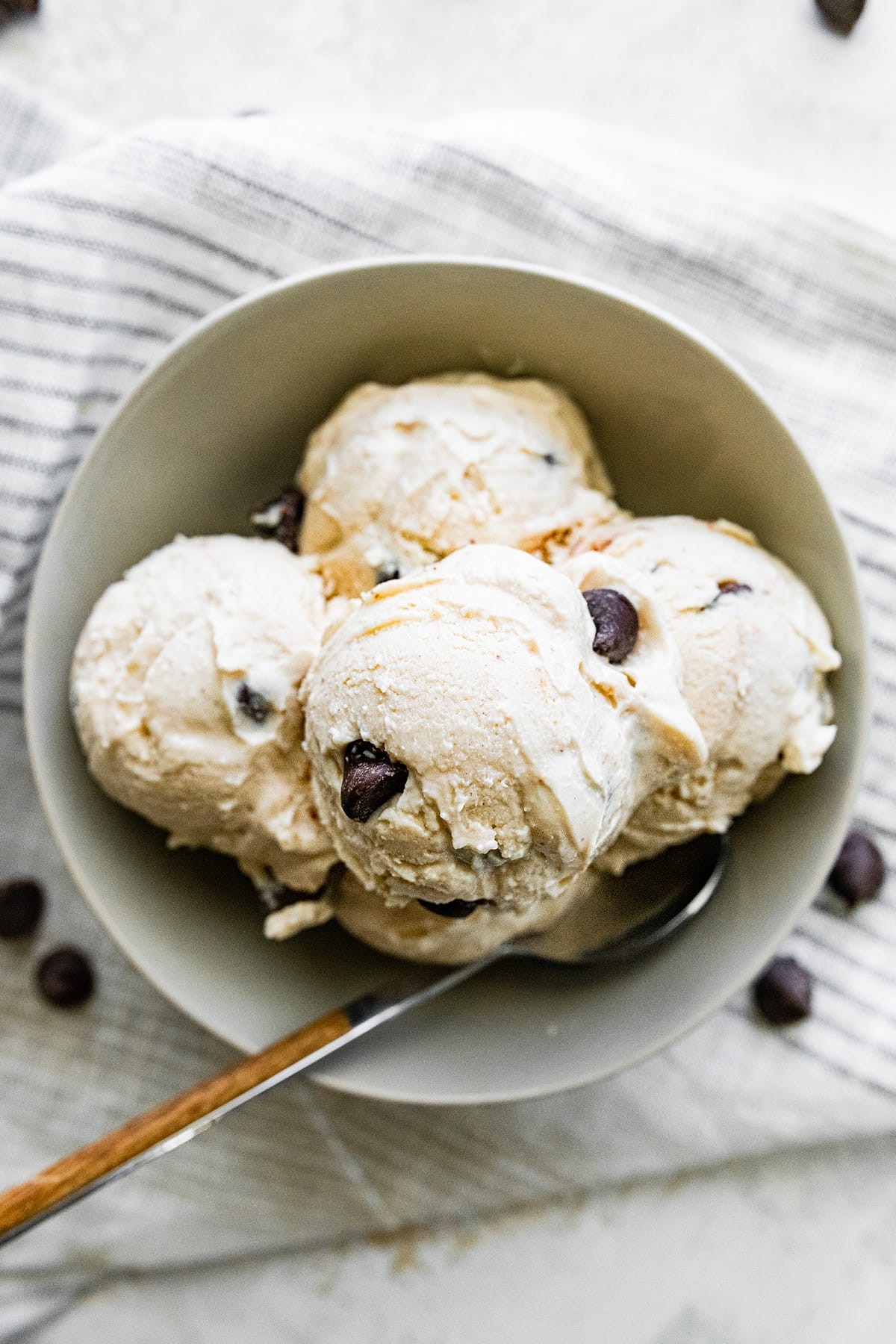 Close-up shot of two coconut yogurt ice cream sandwiches on a plate, with a bowl of extra ice cream in the background.