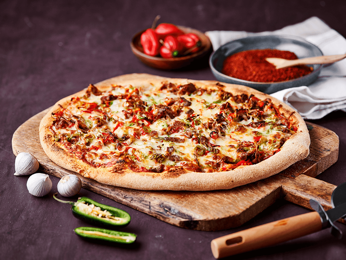 Spicy Beef Rendang Pizza with Chili, close-up shot showing the texture and ingredients
