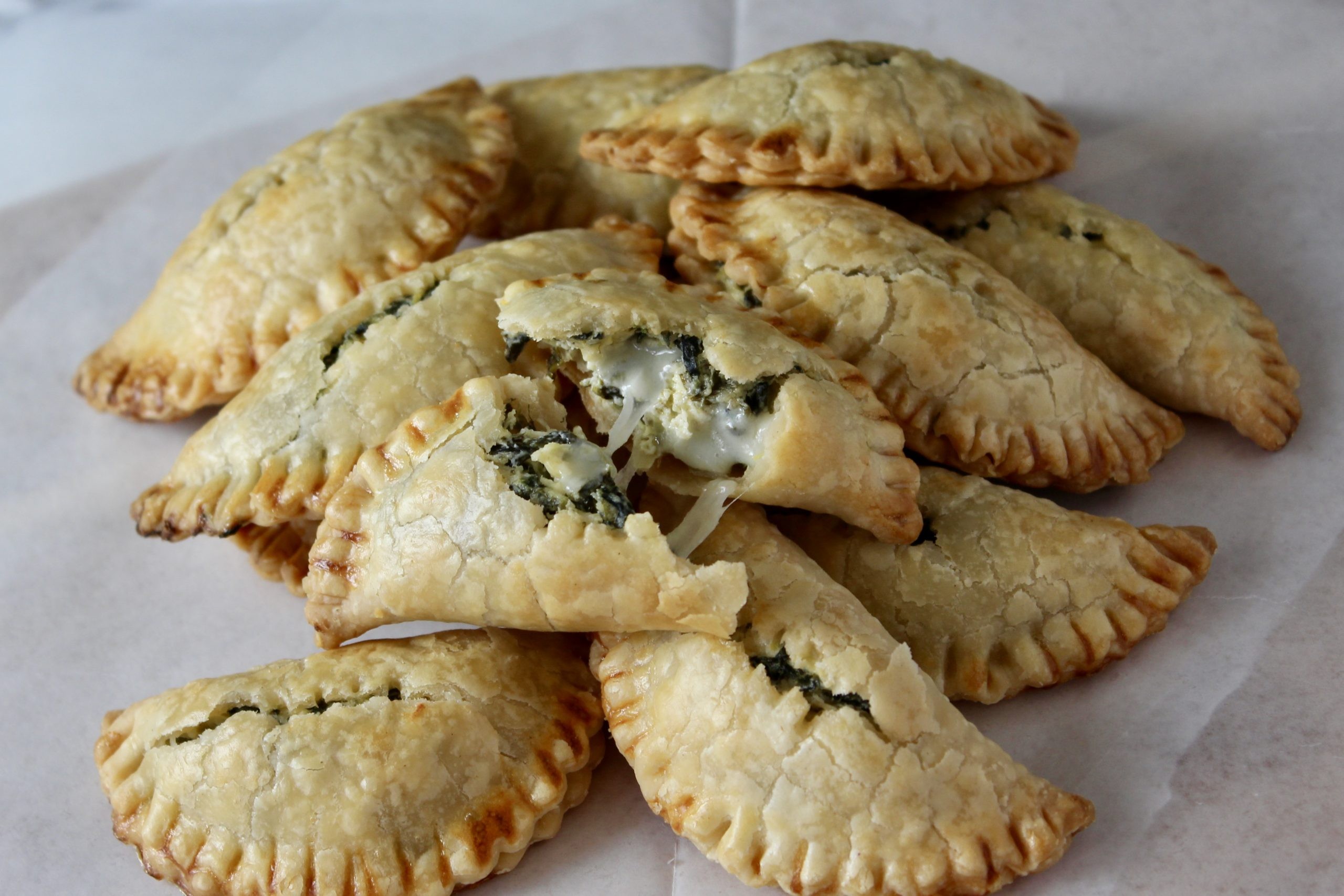 golden brown spinach and artichoke empanadas on a baking sheet