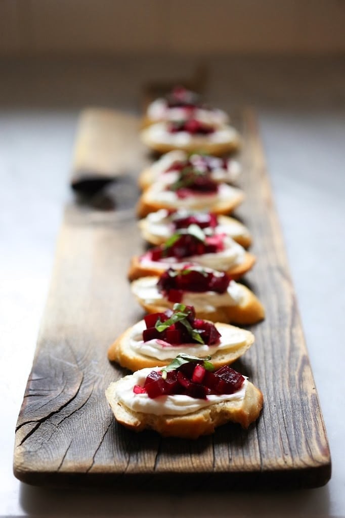Close-up shot of bruschetta with roasted beets and goat cheese on a rustic wooden board