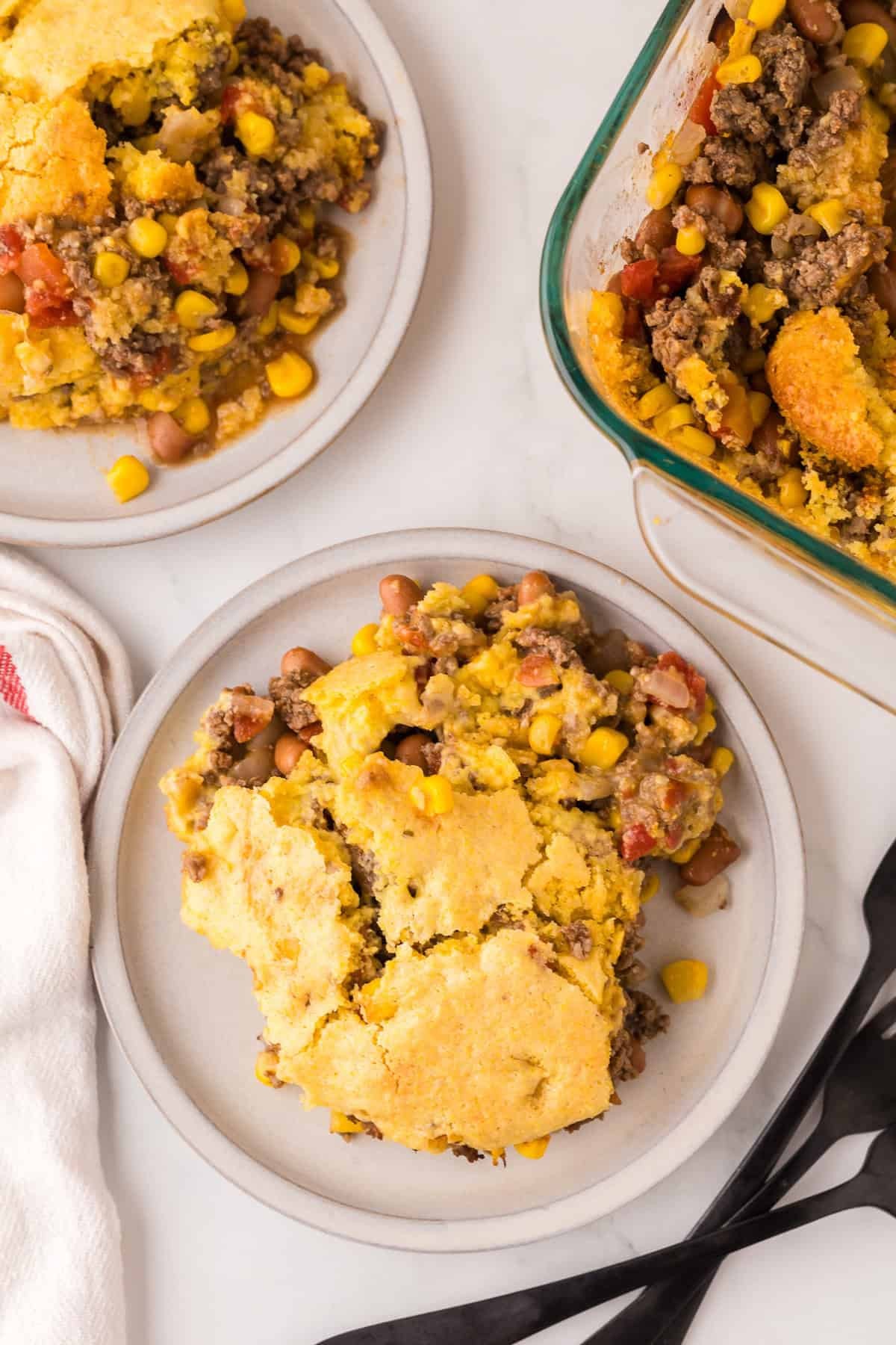 hearty cowboy casserole with golden cheesy topping, ground beef, and corn peeking through in a rustic baking dish