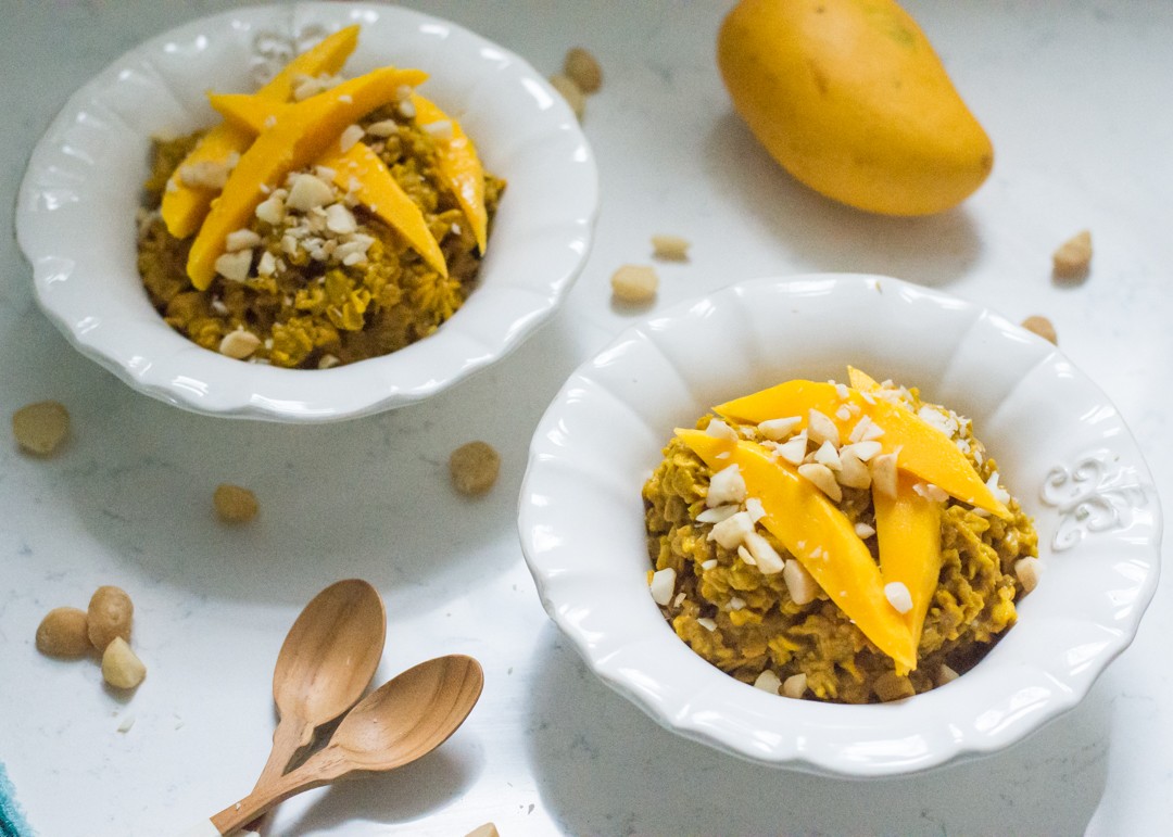 bowl of tropical turmeric oatmeal topped with mango, coconut flakes, and nuts