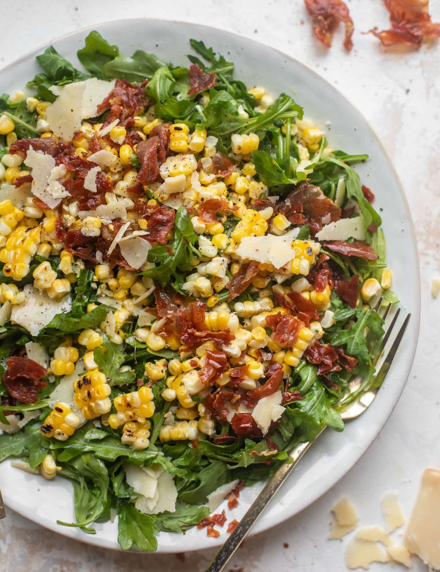 Grilled corn and fig salad with prosciutto on a rustic wooden table