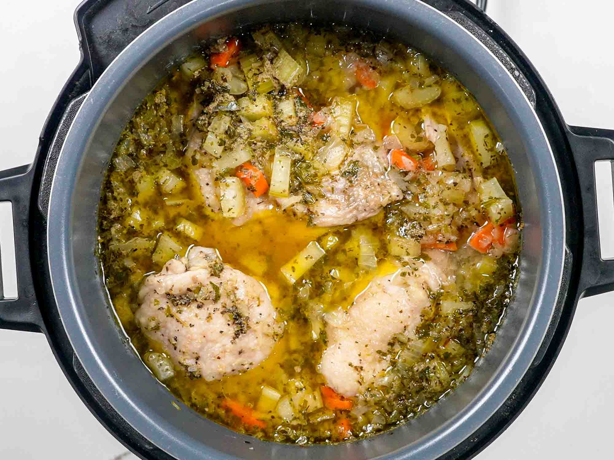 Close-up shot of a steaming bowl of Instant Pot chicken noodle soup, garnished with fresh parsley