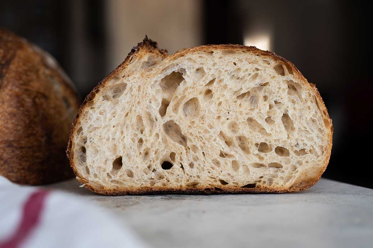 A close-up shot of a perfectly risen sourdough boule with an open crumb structure